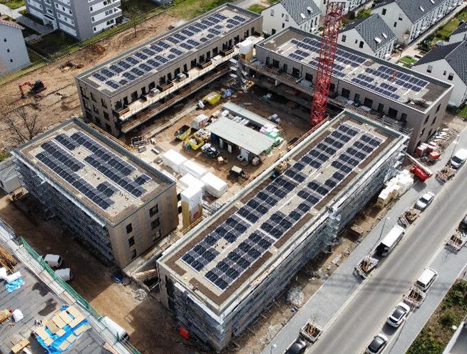 Ein neu gebauter Wohnblock. Auf dem Dach sind Solaranlagen.